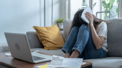 Junge Frau verzweifelt mit Rechnungen am Sofa